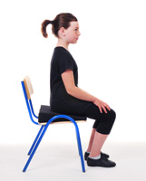 Young girl sitting in chair with improved posture after Alexander lesson