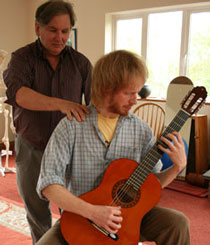 Student learning to play a guitar with less muscle tension and strain