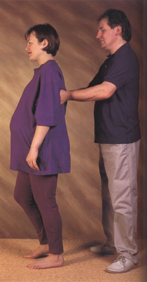 Alexander Technique teacher helping a pregnant woman with her posture while standing